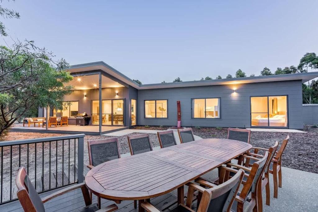 a wooden table and chairs in front of a house at Bonnie - Lakeside Relaxation surrounded by Wineries in Wilyabrup