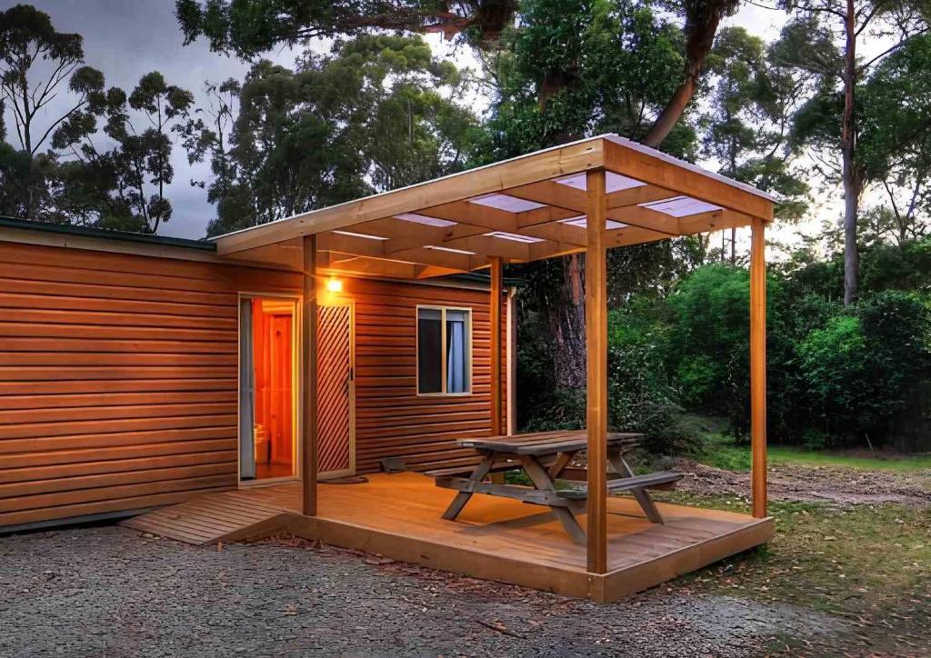 a wooden cabin with a picnic table on a deck at Bruny Island Holiday Park in Adventure Bay