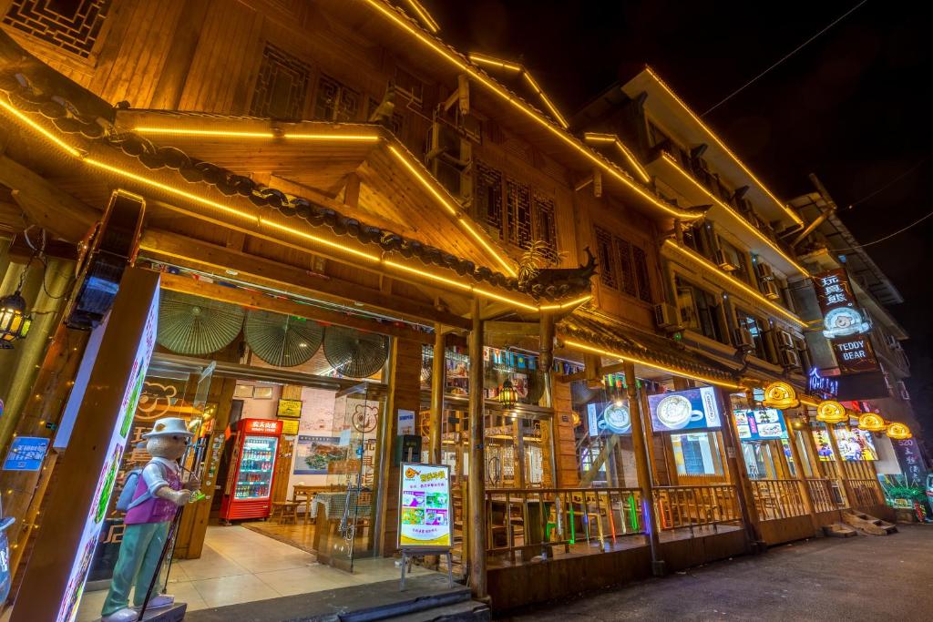 a man standing in front of a store at night at Mount Emei Teddy Bear Hotel玩具熊酒店 in Emeishan City