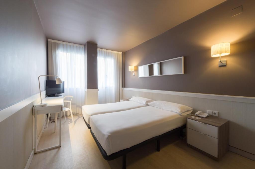 um quarto de hotel com duas camas e uma televisão em Paral·lel em Barcelona