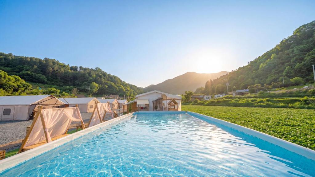 a swimming pool with tents and mountains in the background at Gapyeong ILUGlamping in Gapyeong