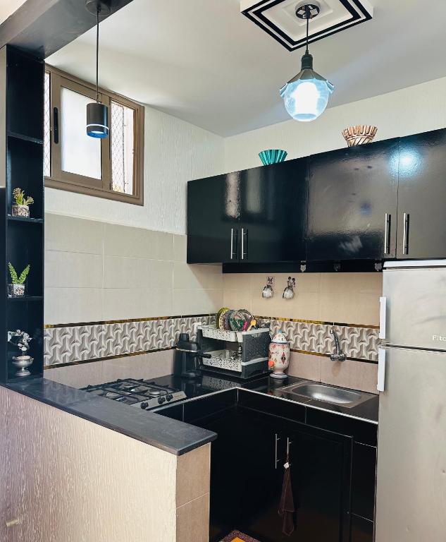 a kitchen with black cabinets and a white refrigerator at Appartement au centre de TIZNIT in Tiznit