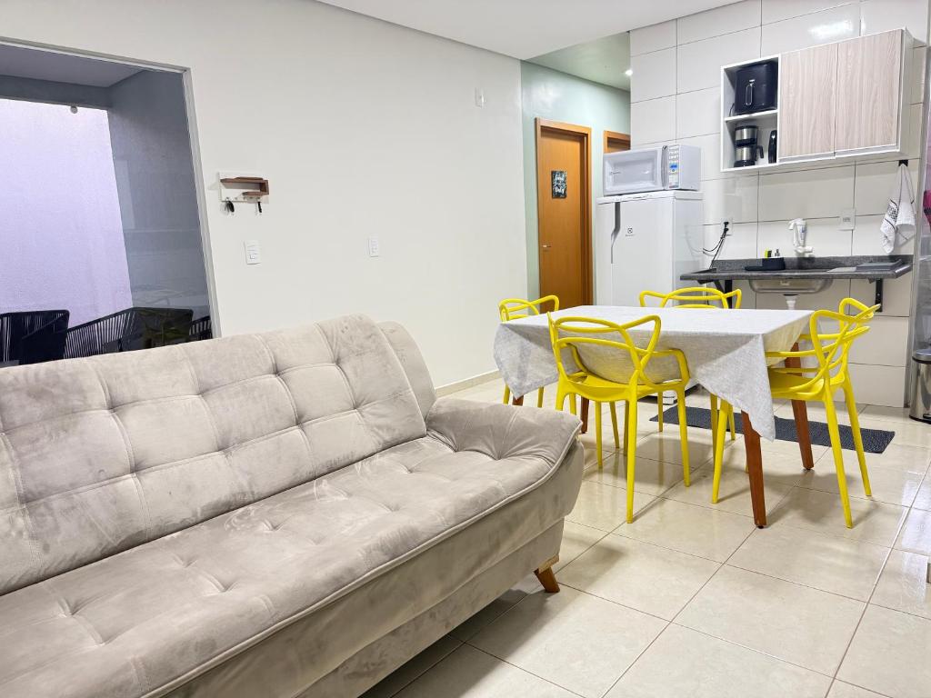 a living room with a couch and a table and yellow chairs at Casa parque 18 in Araguaína