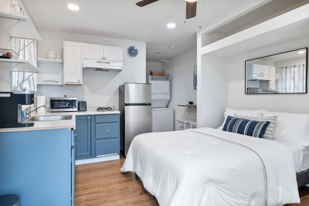 a bedroom with a white bed and a kitchen at Le Petite Willow - Guesthouse in Modesto