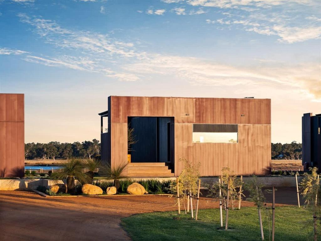 a wooden house with a black door in a field at Samphire Chalet Peppermint - Experience Eco-Luxury in Geographe