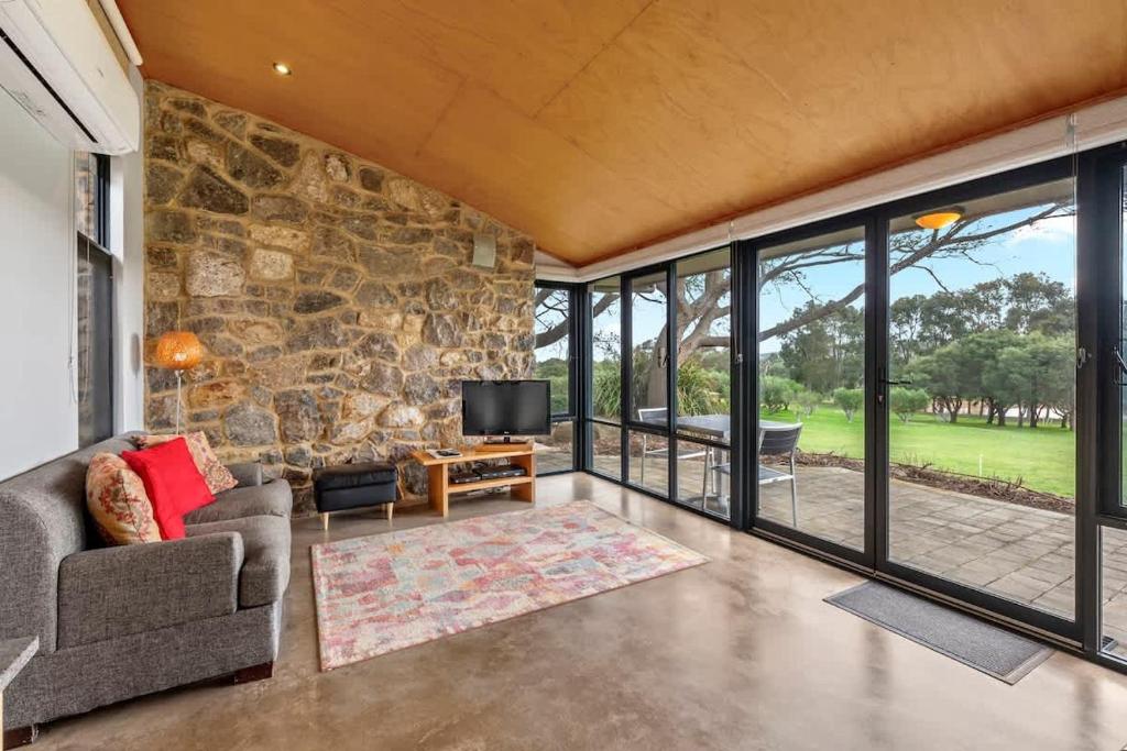 a living room with a stone wall and a tv at Petra Olive 1 in Yallingup