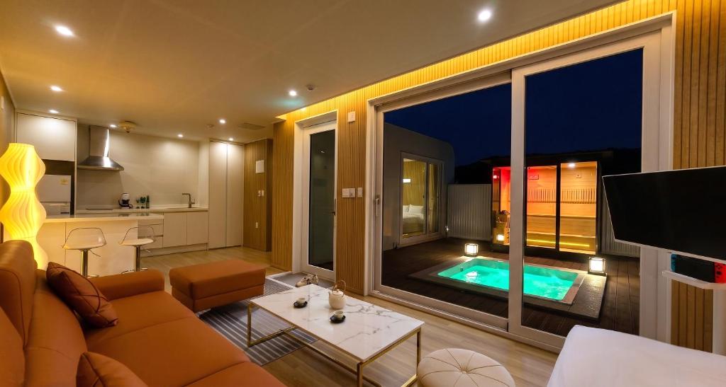 a living room with a large window and a swimming pool at 담양 다움 스파 빌리지 in Haktong-ni