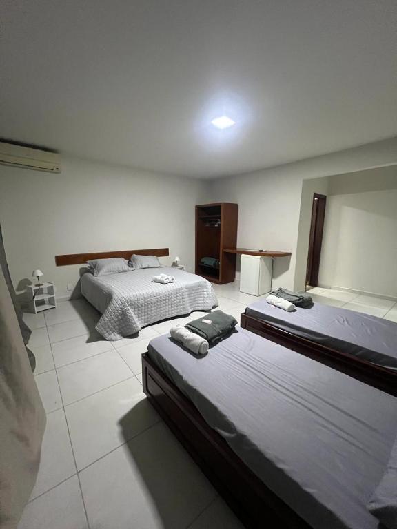 a bedroom with two beds and a table in it at Pousada Boa Praia Guriri in São Mateus