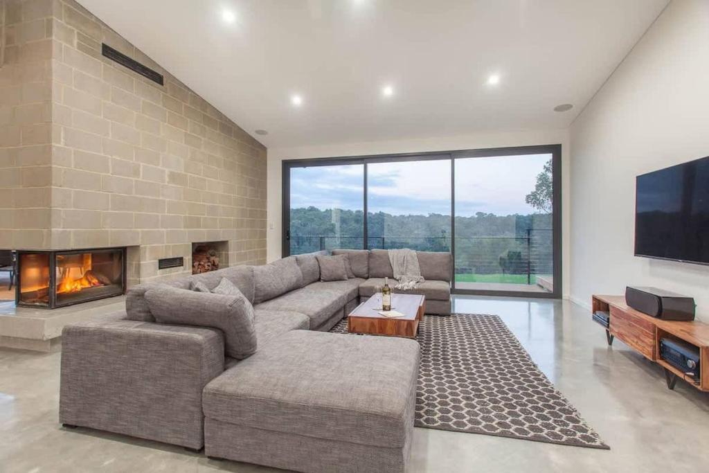 a living room with a large couch and a fireplace at Lake View - Contemporary Comforts meets Nature in Quindalup