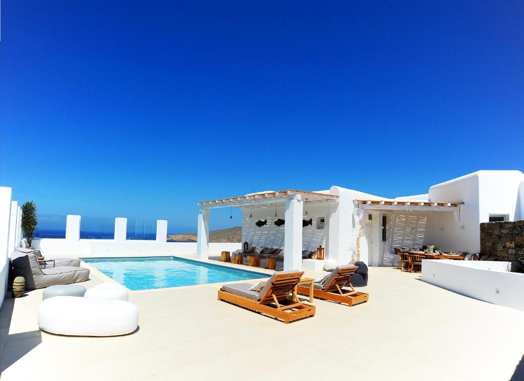 a villa with a swimming pool and chairs and a villa at Lidia Villa in Panormos Mykonos