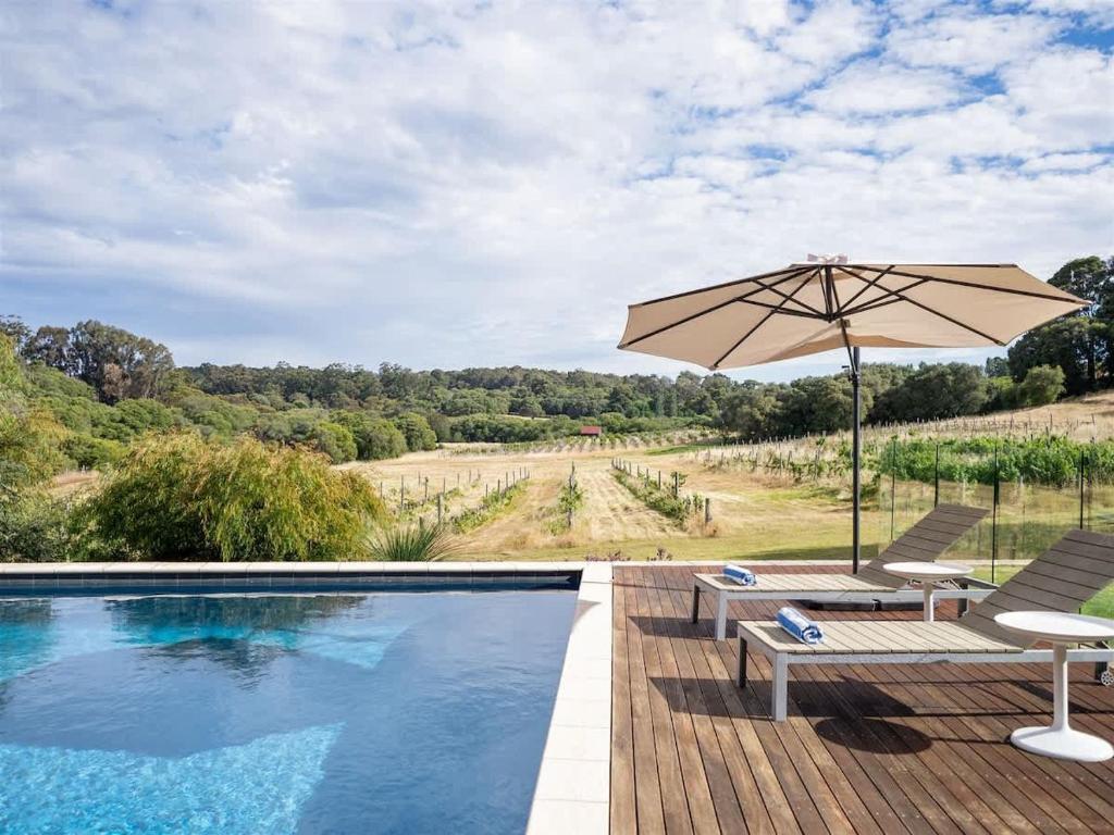 a swimming pool with an umbrella and chairs and a table at Sophie's Vineyard - Sprawling Scenery with Pool in Yallingup