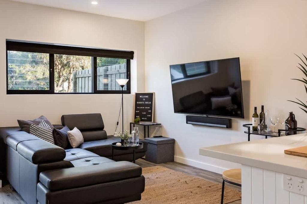 a living room with a couch and a flat screen tv at Rabbits Break - Beachside Bliss Steps from Yallingup in Yallingup