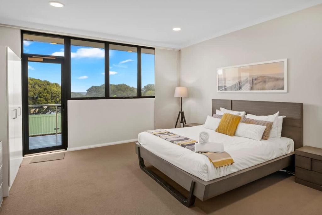 a bedroom with a large bed and large windows at Surfside 3A - Vibrant Yallingup Beachfront Living in Yallingup