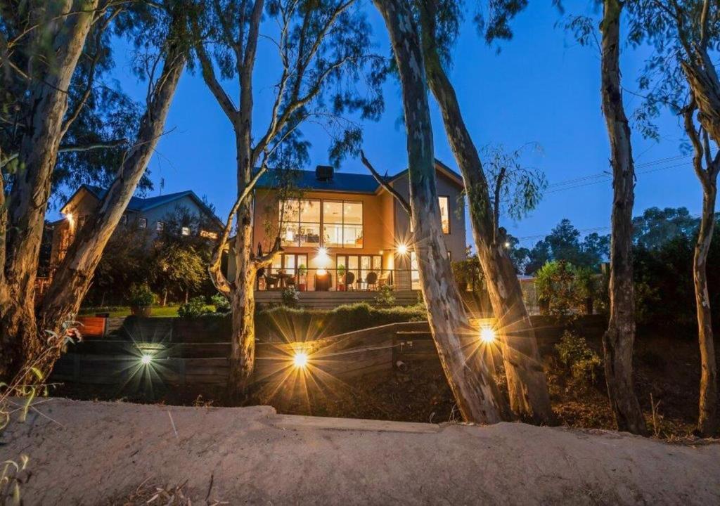 a house with its lights on in the woods at The Gums - Echuca Holiday Homes in Echuca