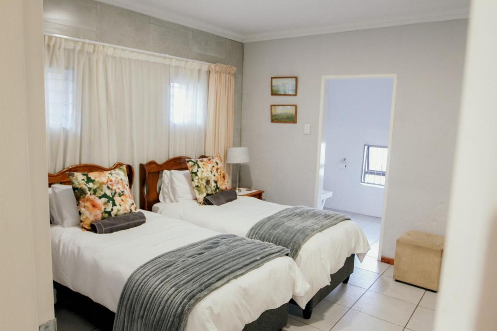 two beds in a room with white walls at Fynbos cottage in Bethlehem
