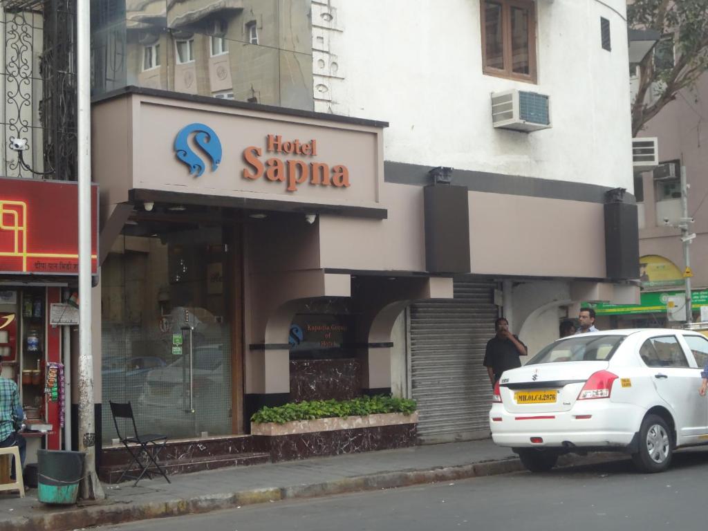 um carro branco estacionado em frente a um hotel saphira em Hotel Sapna em Mumbai