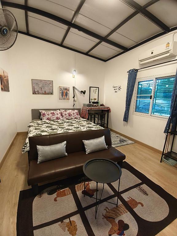 a bedroom with a bed and a couch and a table at บ้านสุขสันต์ พฤกษา45 บางใหญ่ in Ban Nong Kradi