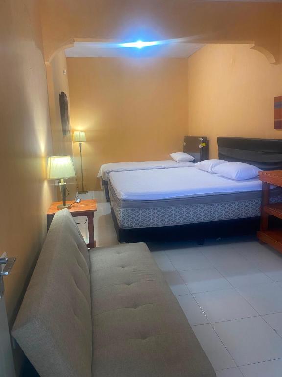 a hotel room with two beds and a couch at Harry & Mimin Homestay in Gorontalo
