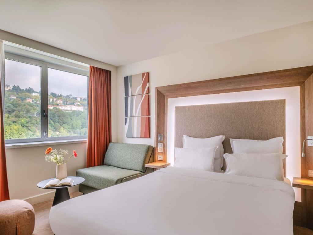 a hotel room with a large bed and a chair at Novotel Lyon Centre-Confluence Bord de Saone in Lyon