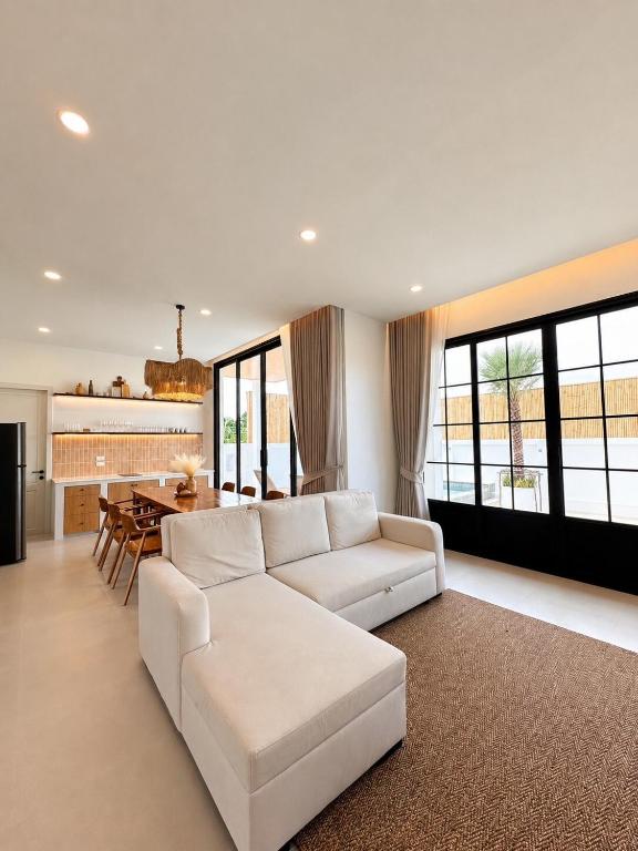 a living room with a white couch and a table at Tim Kanya Pranburi in Pran Buri