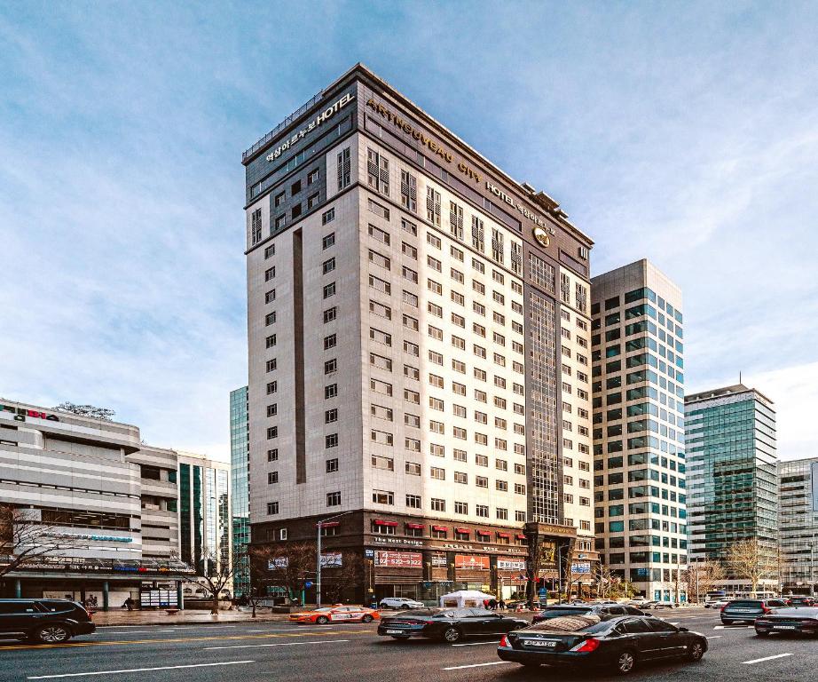 a tall white building with cars on a city street at Yeoksam Artnouveau City Hotel and Residence in Seoul