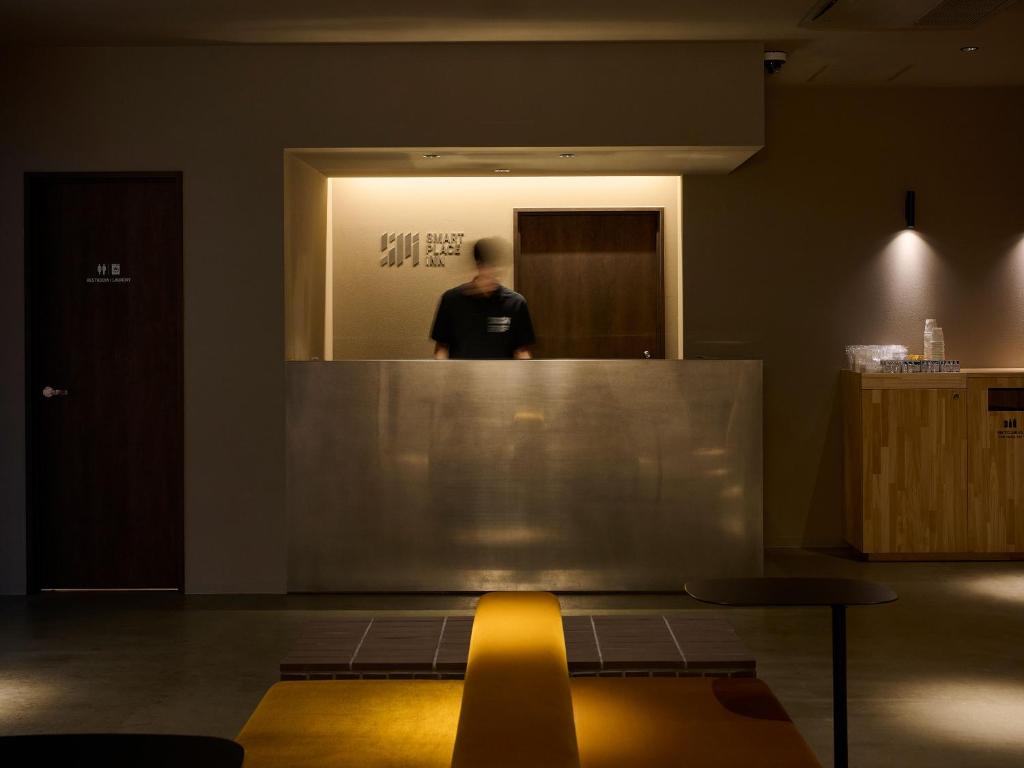 a man standing in a mirror in a room at SMART PLACE iNN Hakata-Gion in Fukuoka