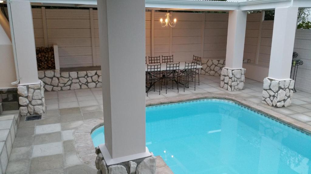 una piscina con columnas y un patio con mesas y sillas en Bergview Guesthouse Swellendam, en Swellendam