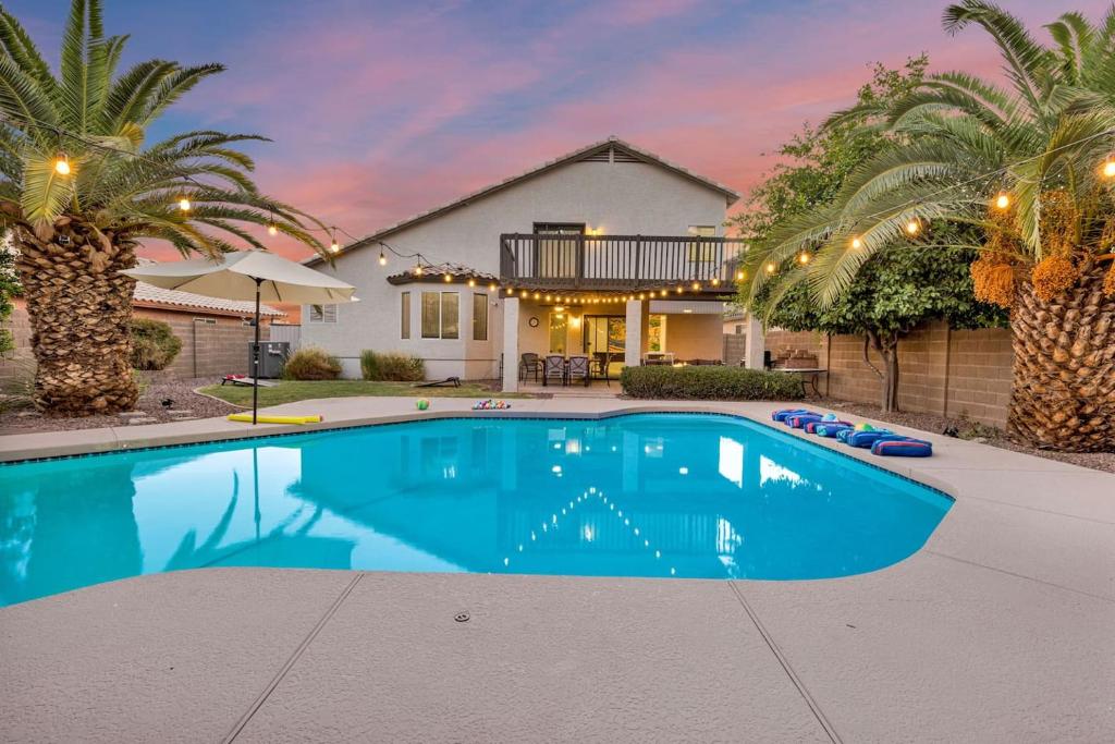 a swimming pool in front of a house with palm trees at Sparkling SaltwtrPoolSpaFirepitFreeNetflixWiFi in Phoenix