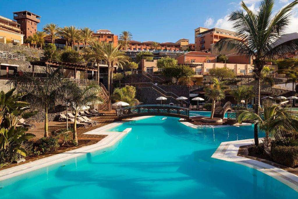 a pool at the resort with palm trees and buildings at Meliá Jardines del Teide - Adults Only in Adeje