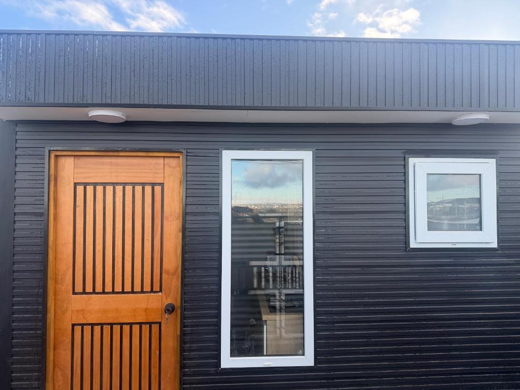 a black house with a door and two windows at Casa monje Patagonia in Puerto Natales