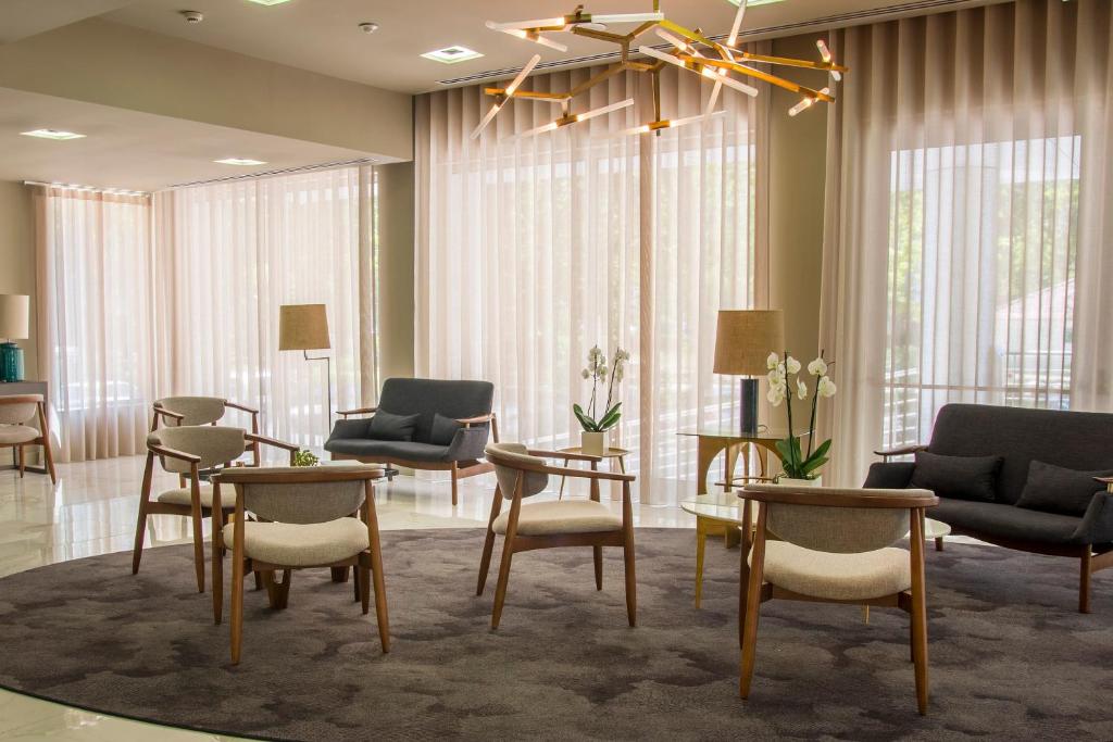 a living room with chairs and tables and windows at Meliá Setúbal in Setúbal