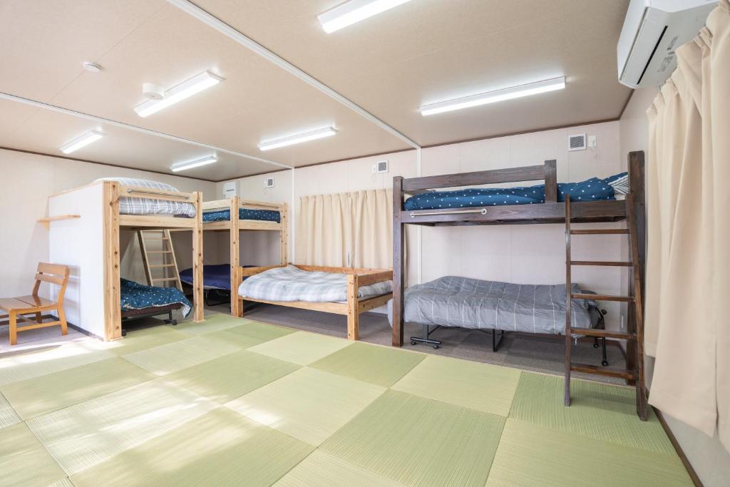 a room with four bunk beds and a green floor at 皓雲庵plus in Miyakonojō