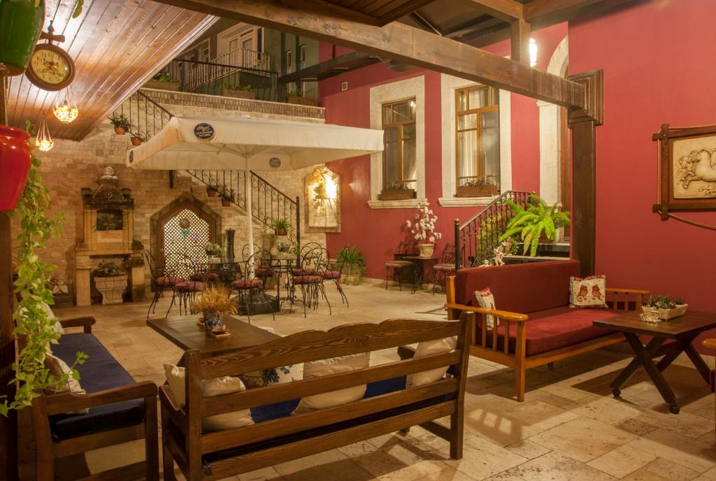 a living room with red walls and a table and chairs at Cankaya Konaklari Hotel in Hatay