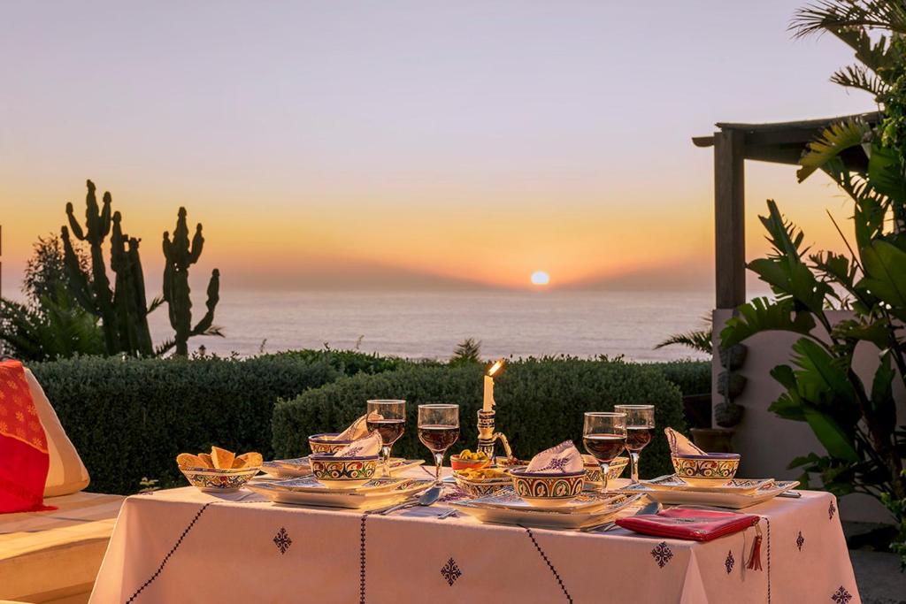 einen Tisch mit Weingläsern und das Meer bei Sonnenuntergang in der Unterkunft Aftas Trip in Mirleft