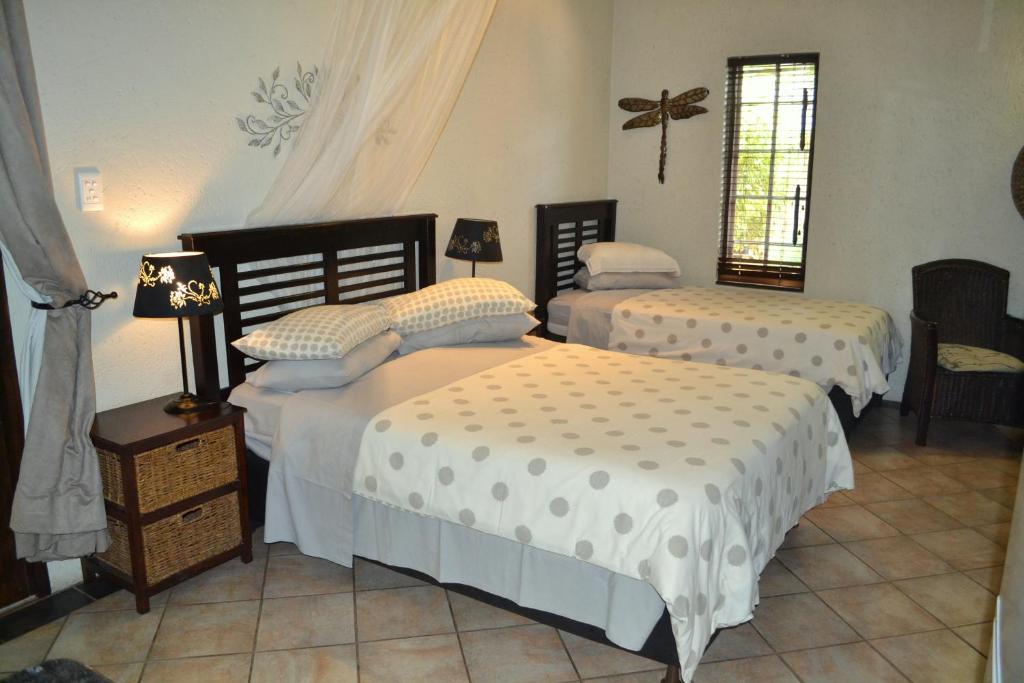 1 dormitorio con 2 camas y ventana en Paradise Creek Lodge en Malelane