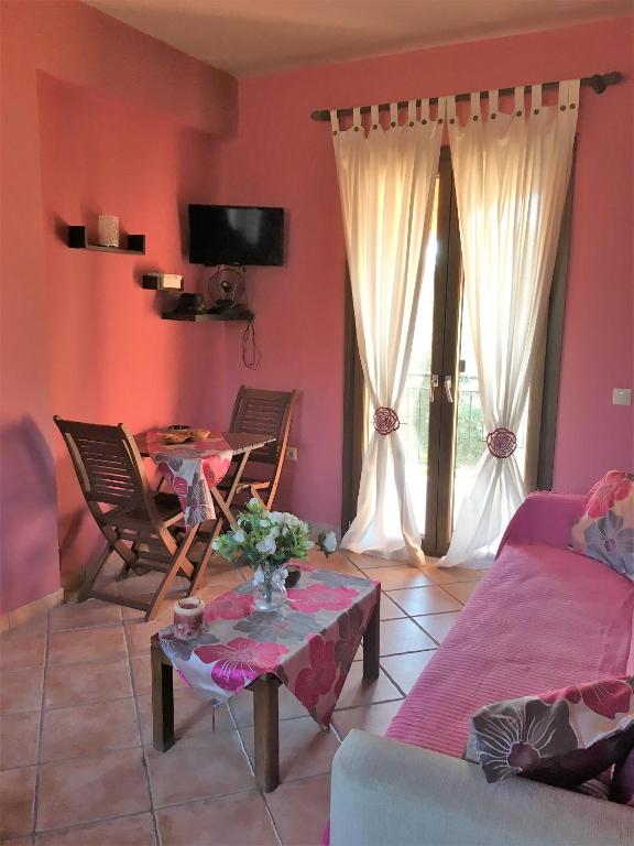 a living room with pink walls and a table and chairs at The Olive Tree House in Kompítsion