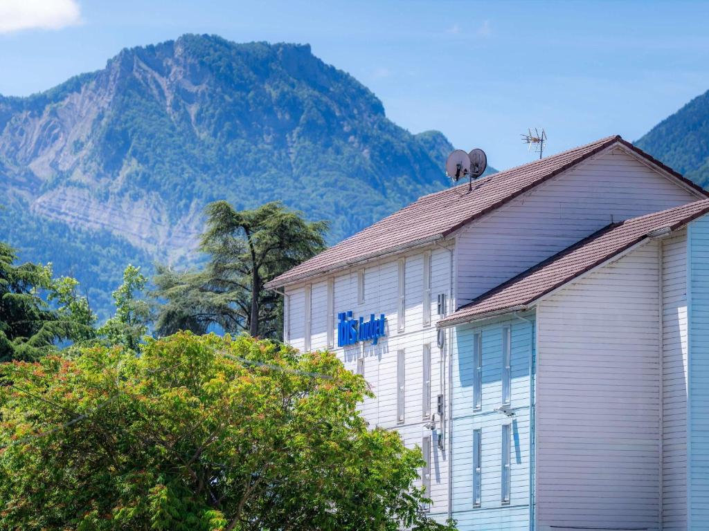 a white building with a mountain in the background at Ibis budget Chambéry Centre Ville- Hôtel Rénové in Chambéry
