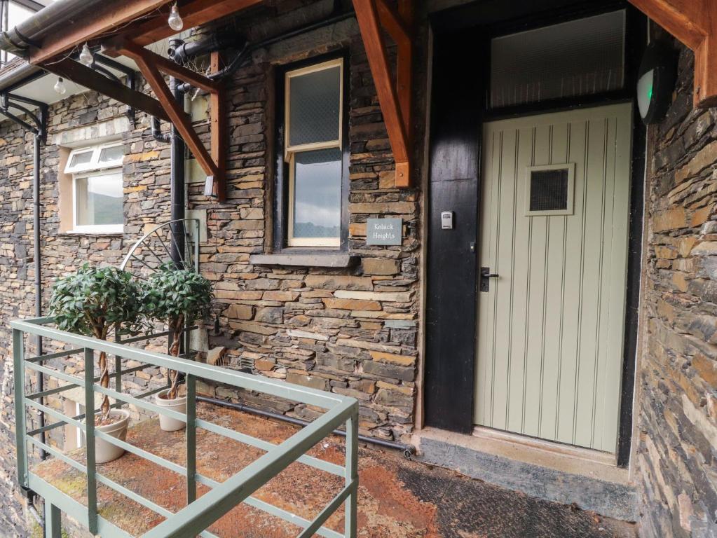 a stone house with a white door and a porch at Kelsick Heights in Ambleside