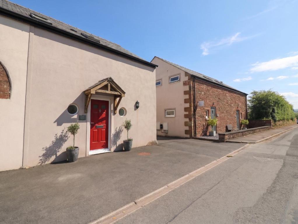 a building with a red door on a street at Coney Garth Barn in Beckermet