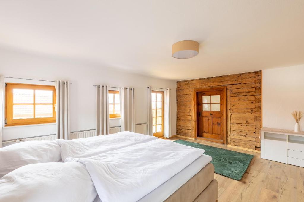 a bedroom with a large white bed and a wooden wall at Ferienhaus - Großer Büchelstein in Grattersdorf