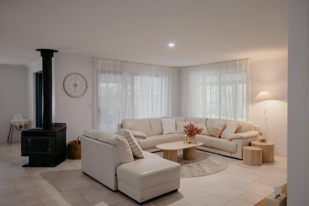 a living room with a white couch and a stove at Luxury at the Cove - Seaside Comfort & Entertainment in Quindalup