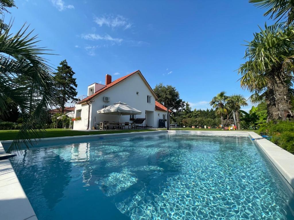 a swimming pool in front of a house at Villa Palma Balatonboglár in Balatonboglár