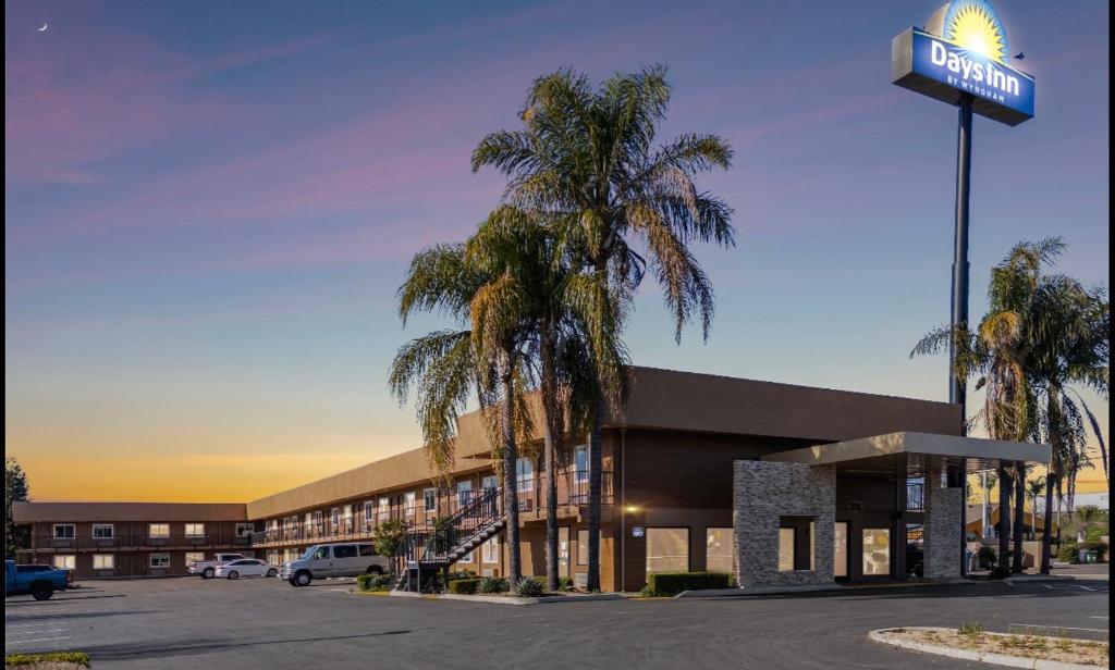 a hotel with palm trees in front of a parking lot at Days Inn Merced / Yosemite Area in Merced