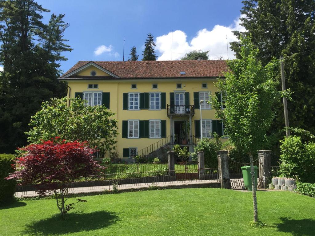 a yellow house with a fence and a yard at BnB villaSteiner in Birrwil