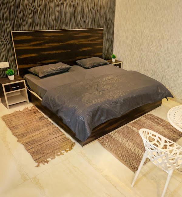 a bedroom with a large bed and two tables and a chair at Royal Orchid in Faridabad