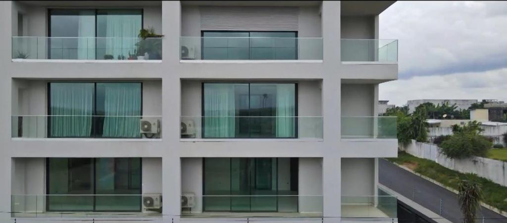 a white building with glass balconies on it at Résidences Aya in Abidjan