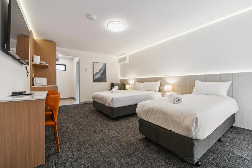 a hotel room with two beds and a television at Frankston Bay Motel in Frankston