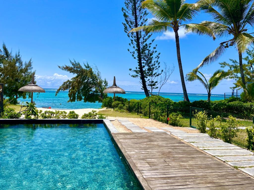a pool with a wooden walkway next to the beach at Breathtaking seaview penthouse - Belle Mare in Post of Flacq