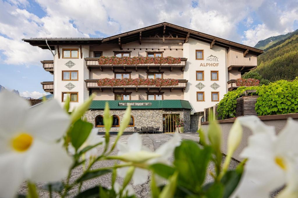 a hotel in the mountains with flowers in the foreground at Hotel Alphof Stubaital in Fulpmes