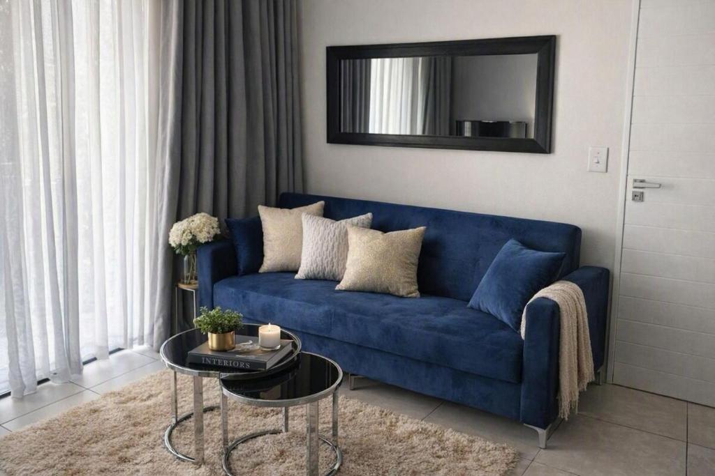 a blue couch in a living room with a mirror at The Blyde Spot in Pretoria